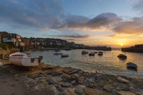 a group of boats in the water at sunset at The Ship Inn in Mousehole