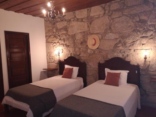 two beds in a room with a stone wall at Casa das Torres da Facha in Ponte de Lima