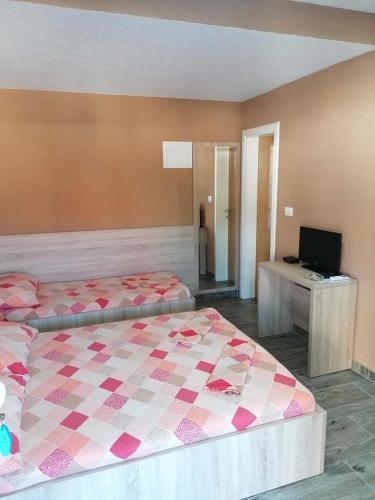 a bedroom with two beds and a desk with a television at Apartmani Babić in Neum
