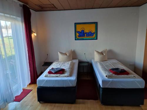 two beds in a small room with a window at Hotel Saarland Lebach in Lebach