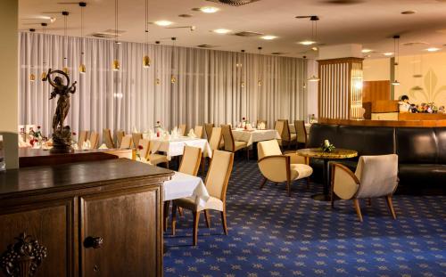 a dining room with white tables and chairs and a restaurant at Dorint Charlottenhof Halle (Saale) in Halle an der Saale