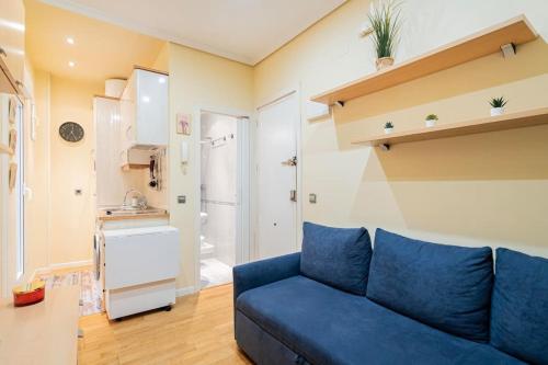 salon z niebieską kanapą i kuchnią w obiekcie Tranquilo apartamento Pacífico/Ciudad de Barcelona w Madrycie