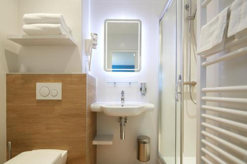 a bathroom with a sink and a toilet at Les Chants d'Ailes - Hôtel Face Mer in La Turballe
