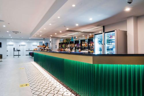 a bar in a restaurant with green at The Benson Hotel in Cairns