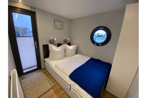 Un dormitorio con una cama azul y blanca y una ventana en Hausboot Fjord Vela mit Biosauna in Barth en Barth