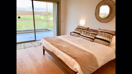 ein Schlafzimmer mit einem Bett mit Spiegel und Fenster in der Unterkunft Golf Tenerife South xx Wheel Accessible Shower xx Free WIFi xx Private Pool 30 degrees xx Two Terraces 30m2x60m2 xxFree Parking xx Mountain view xx Flatscreen 65 inch xx in San Miguel de Abona