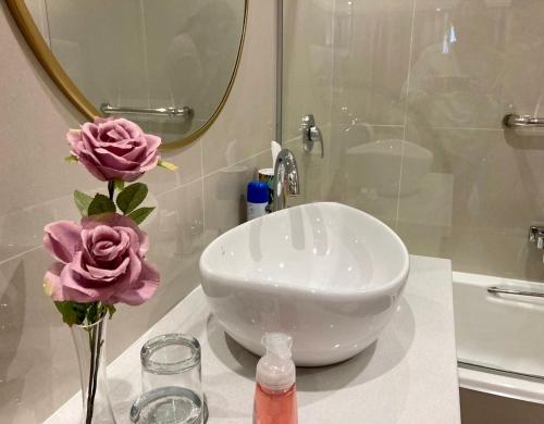 a bathroom with a sink and flowers on a counter at The Ranch Guesthouse in Potchefstroom