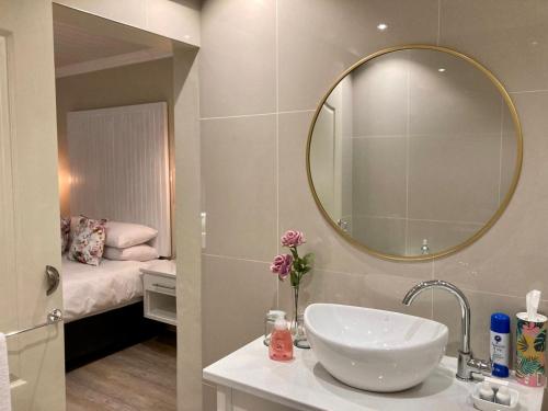 a bathroom with a sink and a mirror and a bed at The Ranch Guesthouse in Potchefstroom