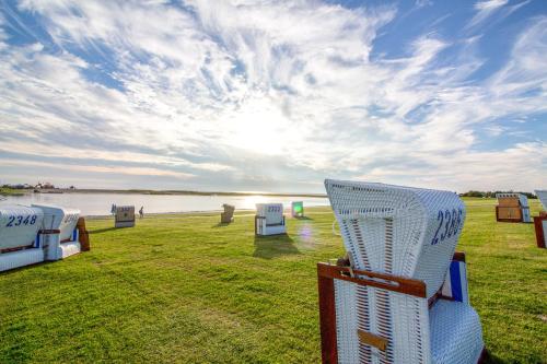 a white wicker chair sitting on the grass near the water at Boutique-Hotel Zur alten Post in Büsum
