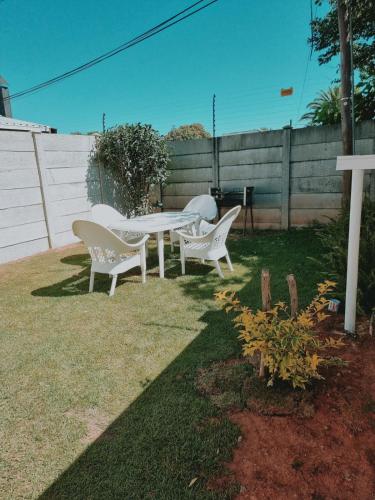 three white chairs and a table in a yard at Danrit Guesthouse - Uncapped wifi in Roodepoort