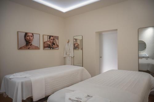a white room with two beds and pictures on the wall at Elkonin Tel Aviv - MGallery Hotel Collection in Tel Aviv