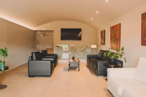 a living room with black leather furniture and a flat screen tv at Hotel Vall de Bas in Joanetes