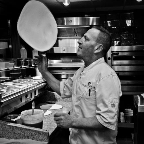 a man standing in a kitchen holding a pan at Hotel De Schout in Denekamp