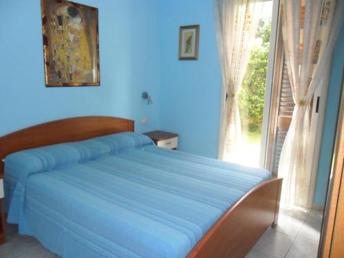 トッレ・スペッキア・ルッジェーリにあるVilla Jolandaの青いベッドルーム(ベッド1台、窓付)