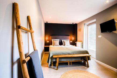 1 dormitorio con 1 cama, TV y silla en Hotel Neptunus en Egmond aan Zee