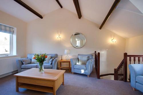 a living room with blue chairs and a table at Norwood Cottage in Kirkby Lonsdale