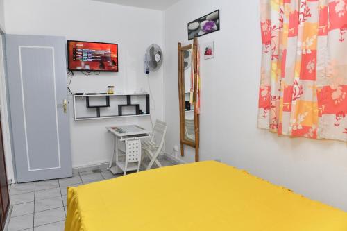 a bedroom with a yellow bed and a desk at Coco et Canne in Port-Louis