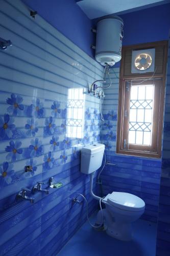 a blue bathroom with a toilet and a window at New Summer Capital in Shimla