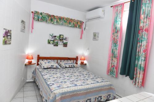 een kleine slaapkamer met een bed en 2 ramen bij Coco et Canne in Port-Louis