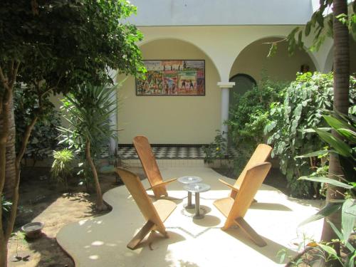 two chairs and a table in a courtyard with trees at KEUR DIAM - Maison de la Paix in Saly Portudal