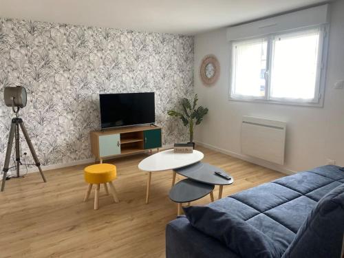 a living room with a couch and a table and a tv at L'échappée Belle in Bessines