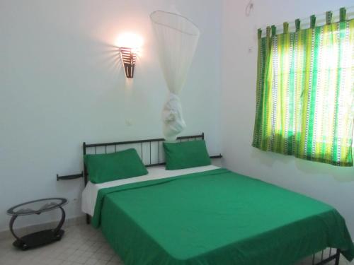 1 dormitorio con 2 camas con sábanas verdes y lámpara en KEUR DIAM - Maison de la Paix en Saly Portudal