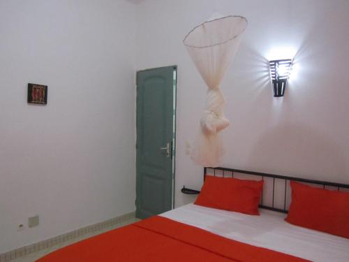 a bedroom with a bed with red pillows and a green door at KEUR DIAM - Maison de la Paix in Saly Portudal