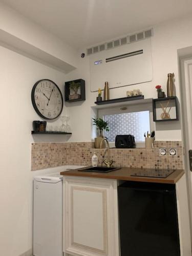 une cuisine avec un comptoir et une horloge au mur dans l'établissement Suite 21 - Clim - front de mer, à Canet
