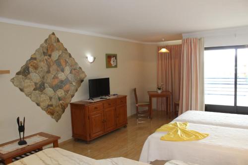 a hotel room with two beds and a television at Naturmar Praia in Albufeira