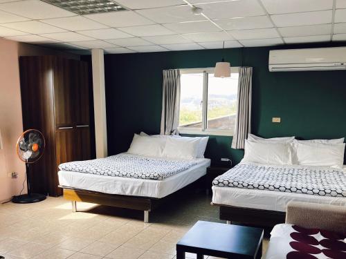 a bedroom with two beds and a green wall at Puli Islet Inn in Puli