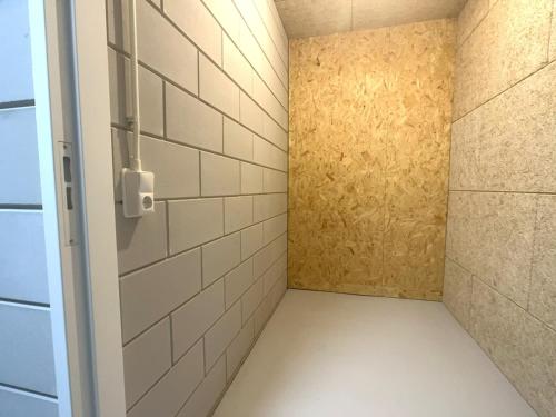 a walk in shower with a white tile wall at Lichthuys 2.02 in Cadzand