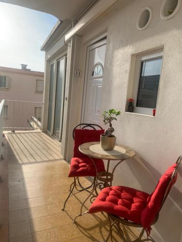 d'un balcon avec une table, des chaises rouges et une porte. dans l'établissement Suite 31 - Clim - front de mer, à Canet