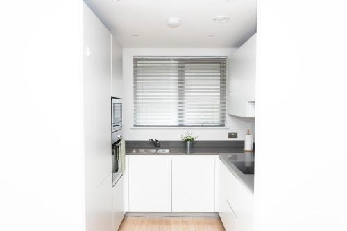 a kitchen with white cabinets and a window at Modern Brixton Apartment in London