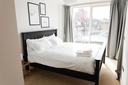 a bedroom with a bed with white sheets and a window at Modern Brixton Apartment in London