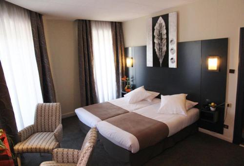 a hotel room with a bed and two chairs at Hôtel Le Bristol Strasbourg Gare in Strasbourg