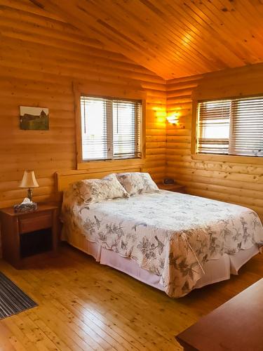 ein Schlafzimmer mit einem Bett in einer Holzhütte in der Unterkunft Hillside Cottages in Bay Roberts
