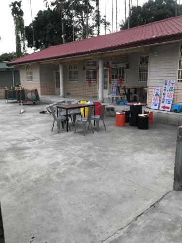 a patio with a table and chairs in front of a building at 嘉義行滿旅宿&包棟親子寵物烤肉平價好趣宿 in Zhuqi