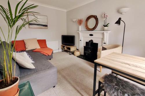 a living room with a couch and a fireplace at May Cottage - Heart of Vibrant Village & 10 mins Walk to Beach in Milford on Sea