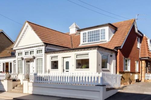 a white house with a white fence at May Cottage - Heart of Vibrant Village & 10 mins Walk to Beach in Milford on Sea