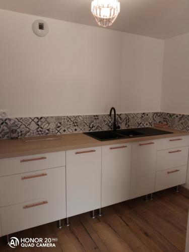 a kitchen with white cabinets and a sink at Studio24 in Trélissac