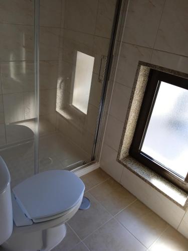 a bathroom with a toilet and a shower and a window at Isabel de Gouveia in Belmonte