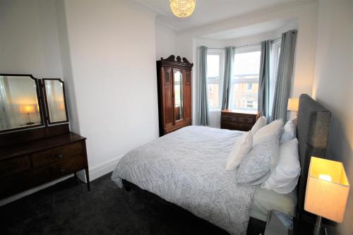 a bedroom with a bed and a dresser and a mirror at Large Period Property - Beautifully Refurbished in Newcastle upon Tyne