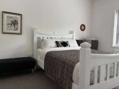 a bedroom with a white bed and a black ottoman at Contemporary Townhouse Stunning lakeside location in Belturbet