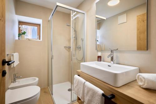 La salle de bains est pourvue d'un lavabo blanc et d'une douche. dans l'établissement Ciasa Col Cuch, à La Villa