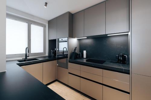 a kitchen with black and brown cabinets and a window at Andermatt Alpine Apartments in Andermatt