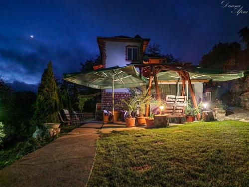 una casa con un paraguas en el patio por la noche en Къща за гости Марчела и Ресторант Мъри, 