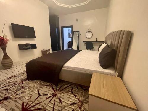 ein Schlafzimmer mit einem großen Bett und einem TV in der Unterkunft PH Apartment, Wuye in Abuja
