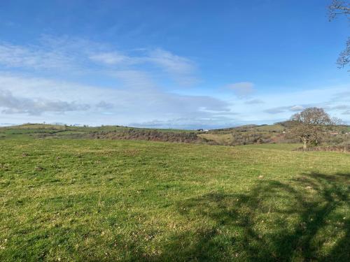 a field of green grass with a hill in the background at Luxury Mary's Croft with Swedish Hot tub and BBQ HUT in Shrewsbury