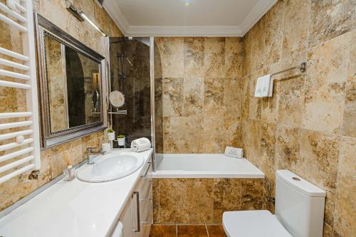 a bathroom with a tub and a sink and a toilet at The Central Collection Apartments in Chişinău