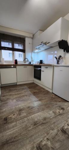 uma cozinha vazia com armários brancos e piso de madeira em Retreat SoloHike em Mörel